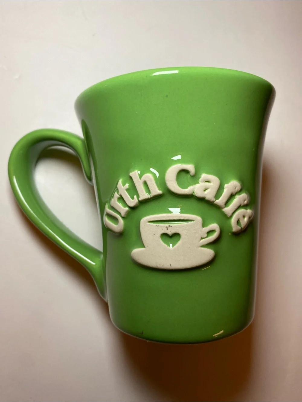 Urth Cafe ceramic coffee mug in green with white embossed logo